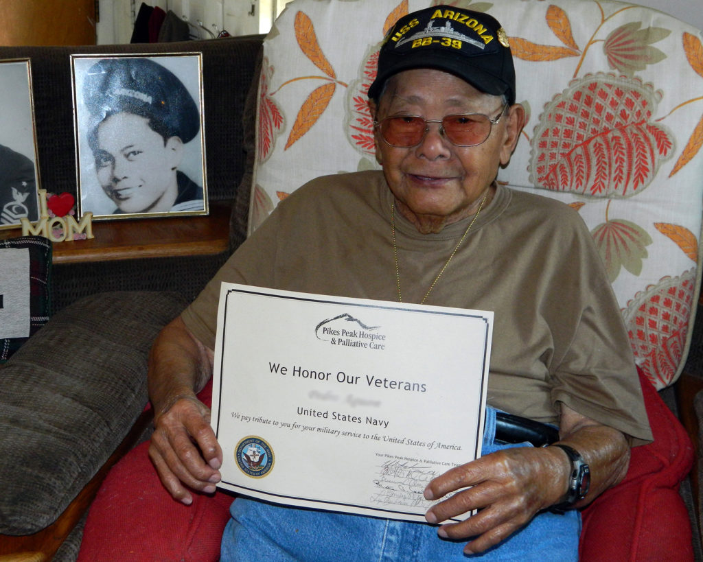 Veteran wearing a USS Arizona hat holding their We Honor Veterans certificate.