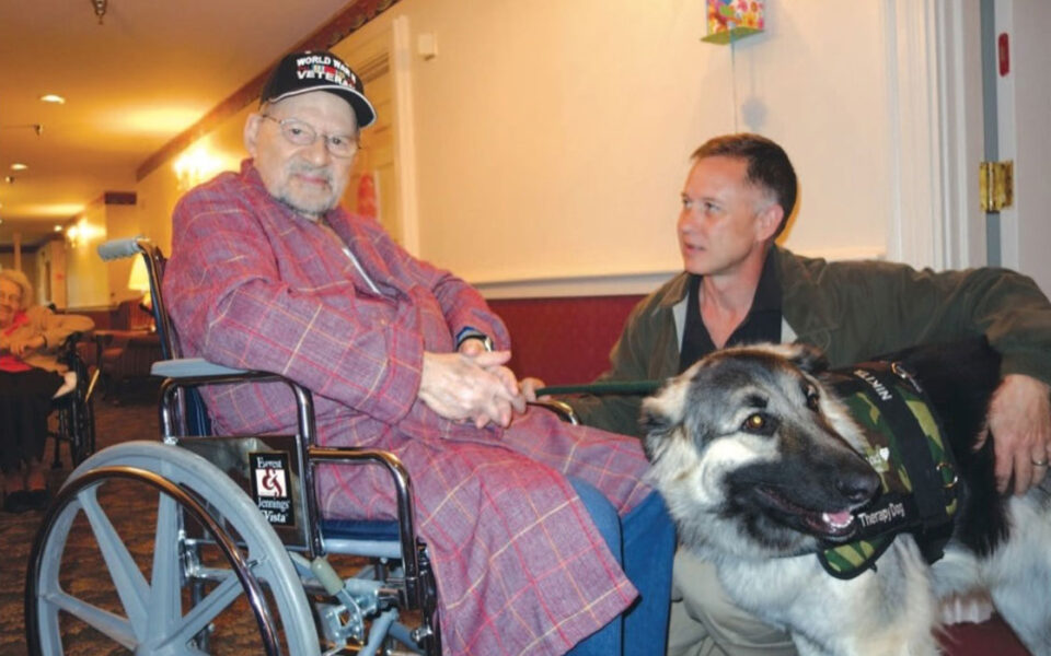 A Hospice Care team member and their service dog meets with a Veteran.